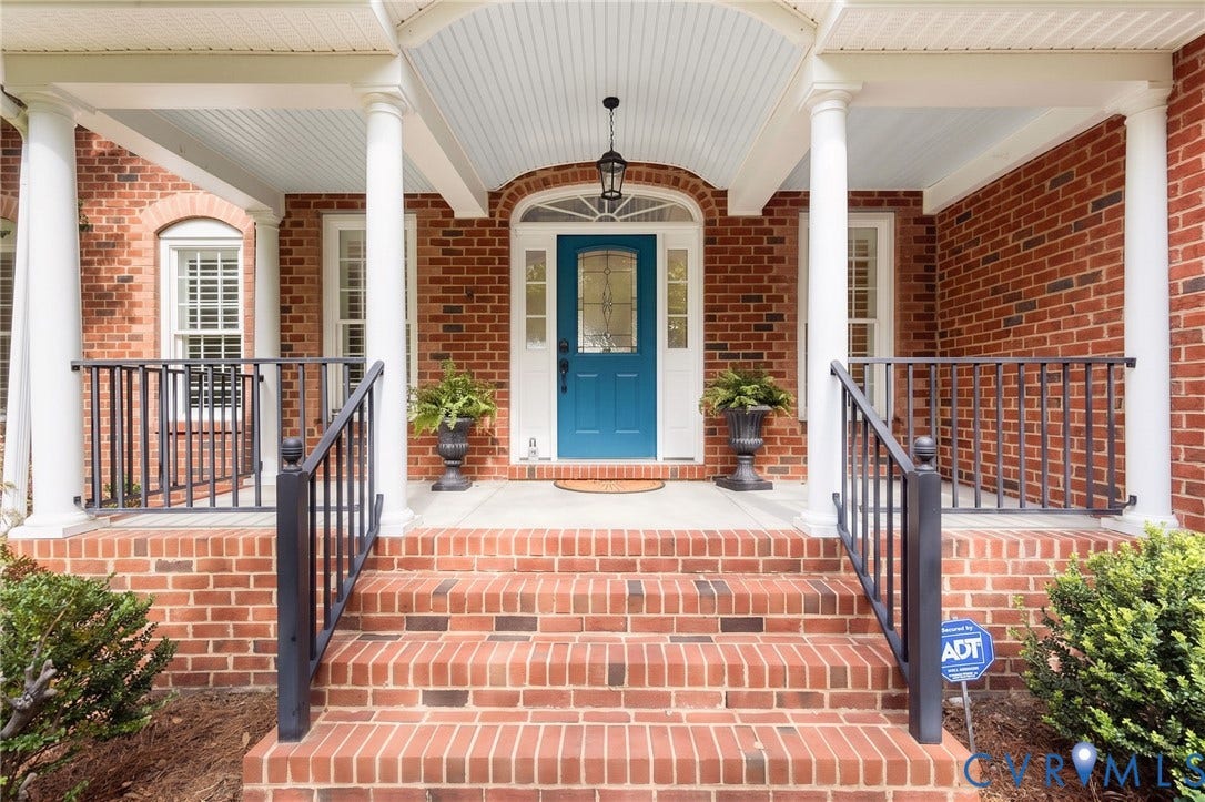 12669 Fawn Lane, Goochland, VA 23233 Brick exterior featuring a covered porch with white columns, a blue front door with decorative glass, and a brick staircase with dark railings