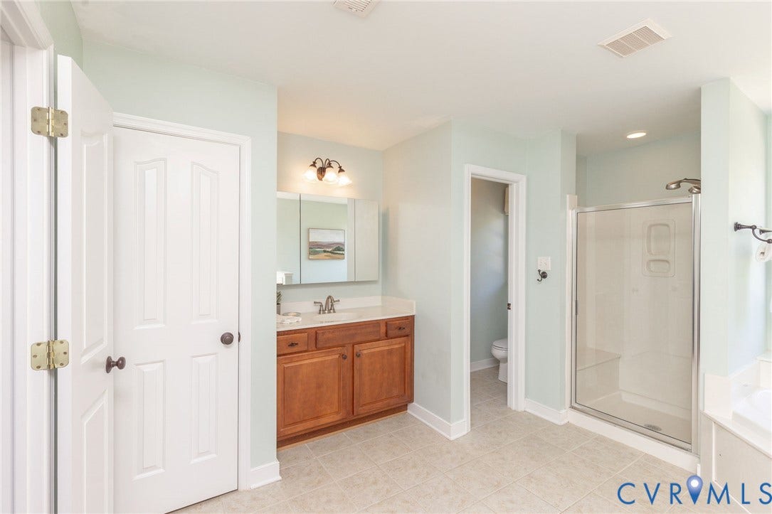 12669 Fawn Lane, Goochland, VA 23233 Tiled flooring with a glass-enclosed shower, a double vanity with a light-toned countertop, and a built-in tub