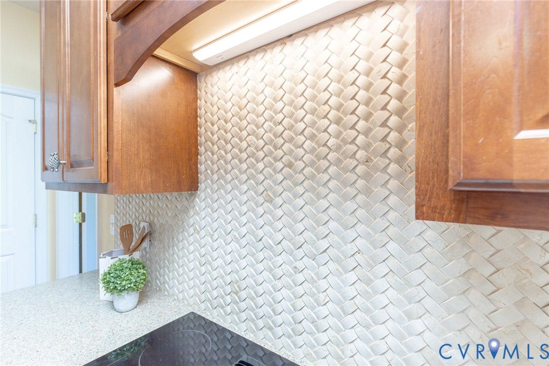 12669 Fawn Lane, Goochland, VA 23233 Woven tile backsplash with under-cabinet lighting, wood cabinetry, and a solid surface countertop