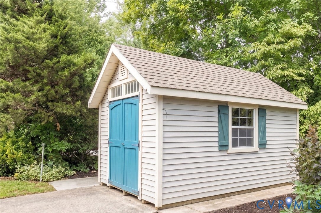 12669 Fawn Lane, Goochland, VA 23233 Gable-roof storage shed featuring light gray siding, teal double doors, a white-framed window with teal shutters, and shingle roofing