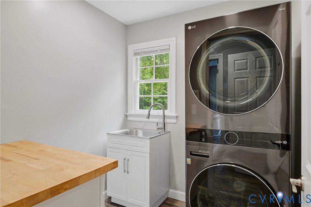 11150 Hames Lane, Glen Allen, VA 23059 Laundry area featuring a stacked washer and dryer, stainless steel utility sink with a chrome faucet, white cabinetry, wood-finish countertop, and a window