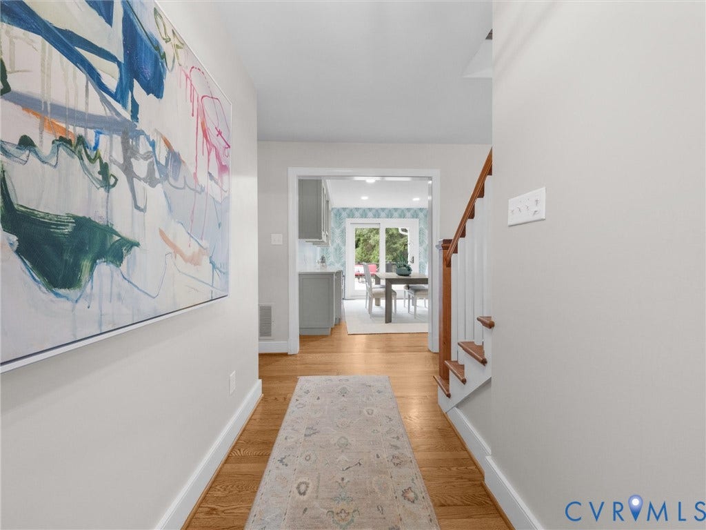 600 Baldwin Road, Henrico, VA 23229 Hardwood flooring, painted interior walls, wood staircase with white risers, doorway leading to an additional space, and a kitchen with grey cabinetry