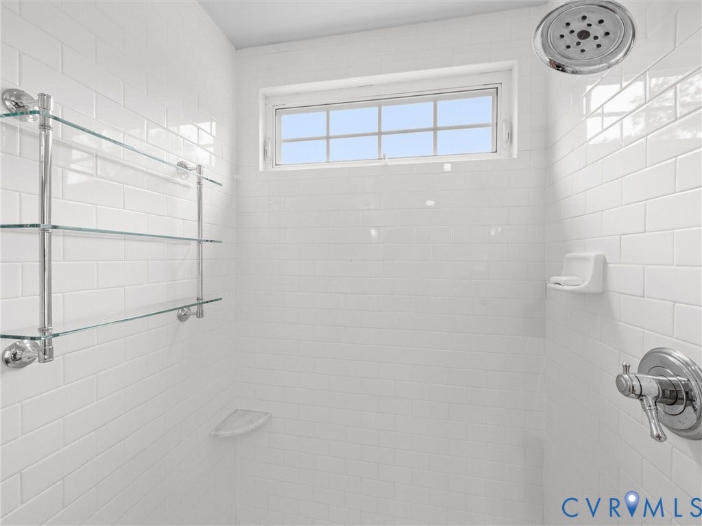600 Baldwin Road, Henrico, VA 23229 Shower with white subway tile, a chrome shower head, a chrome shower control, three glass shelves, and a transom window