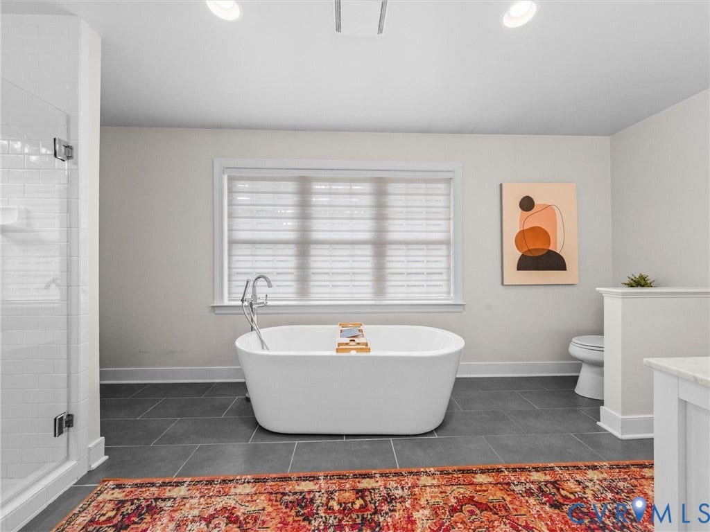 600 Baldwin Road, Henrico, VA 23229 Freestanding soaking tub with floor-mounted faucet, walk-in shower with glass enclosure and subway tile, dark gray floor tiling, and recessed ceiling lighting