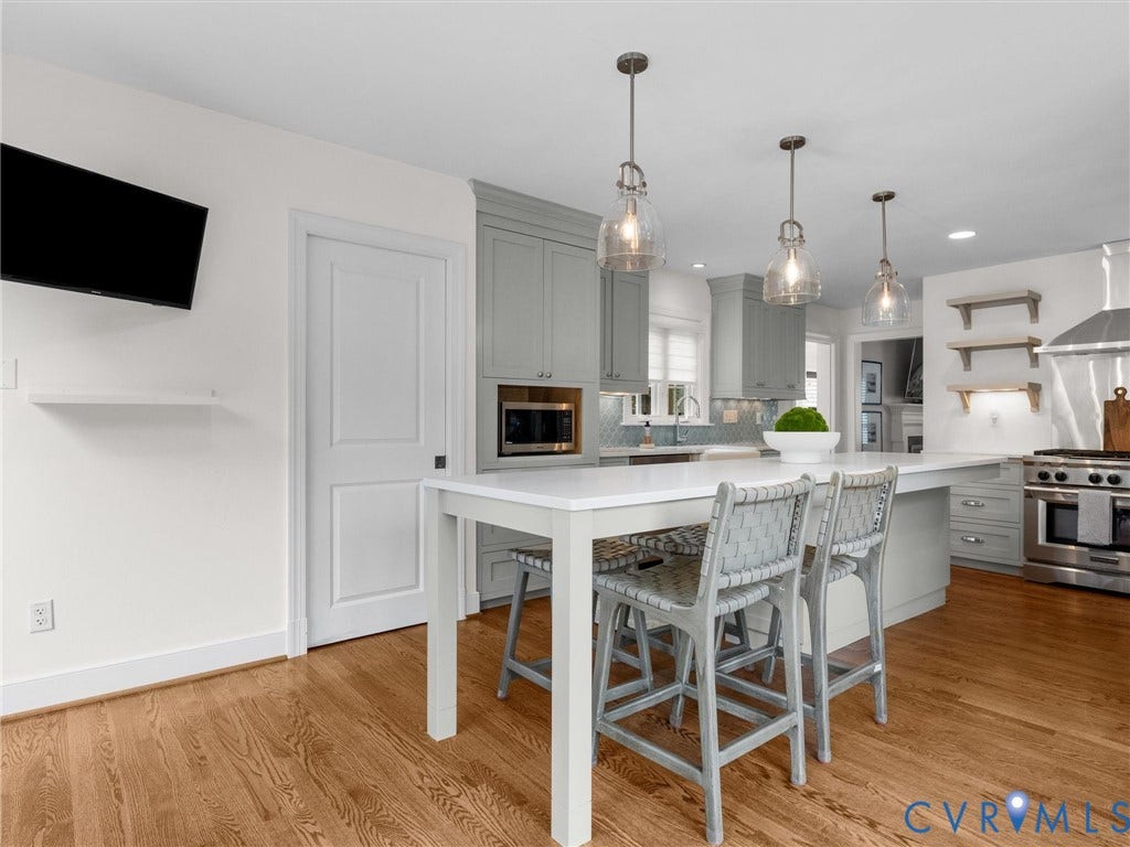 600 Baldwin Road, Henrico, VA 23229 Kitchen featuring wood-finish flooring, an expansive island with countertop seating, three pendant lights, custom cabinetry, and stainless steel appliances