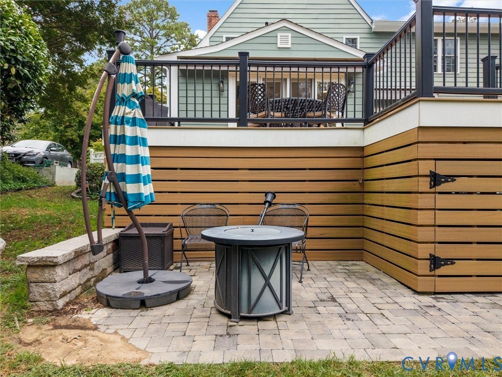 600 Baldwin Road, Henrico, VA 23229 Paved patio area, stone retaining wall, composite deck with black railings, horizontal wood-look siding, and integrated storage with black hardware
