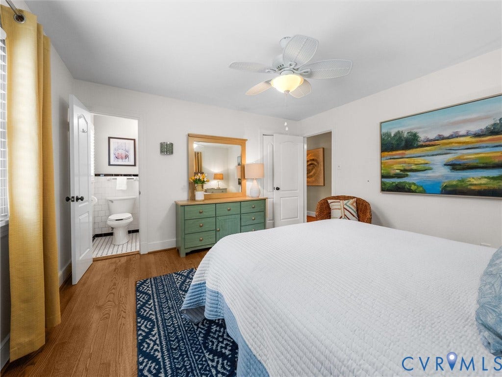 600 Baldwin Road, Henrico, VA 23229 Spacious primary bedroom with wood-finish flooring, ceiling fan with integrated lighting, and a green-painted dresser with mirror
