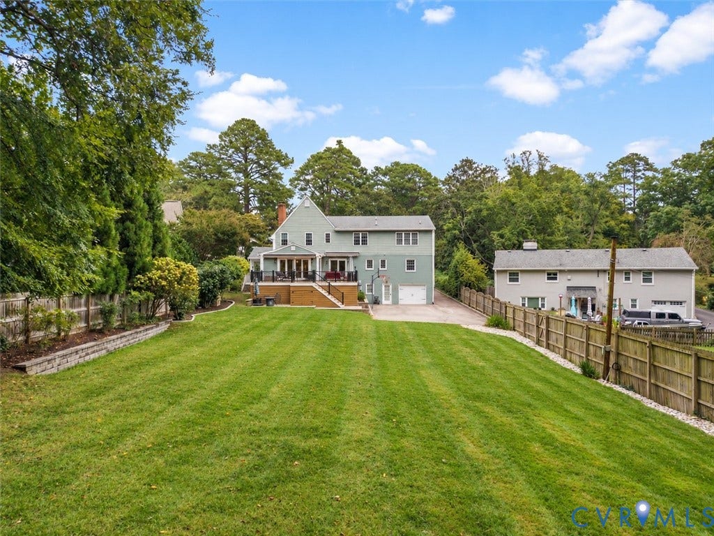 600 Baldwin Road, Henrico, VA 23229 Expansive rear lawn with mature perimeter trees, a stone retaining wall, and a raised wooden deck with railings