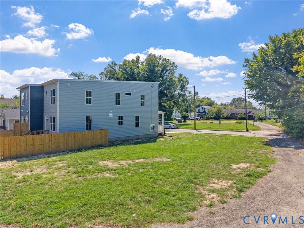 2000 Newbourne Street, Richmond, VA 23223 New construction residence featuring light blue and dark blue siding, multiple windows, and a wood privacy fence