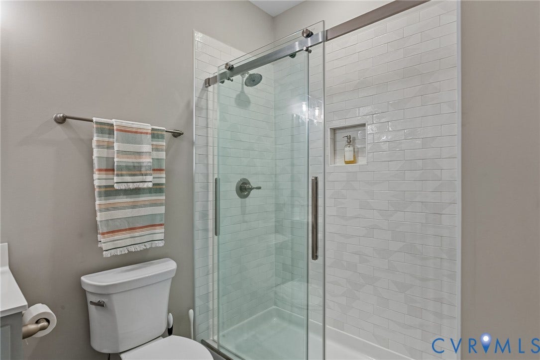 13003 Farrington Place Lane, Farrington Place, Hanover, VA 23059 Glass-enclosed shower with a sliding door, subway tile surround, built-in shower niche, and a rain showerhead