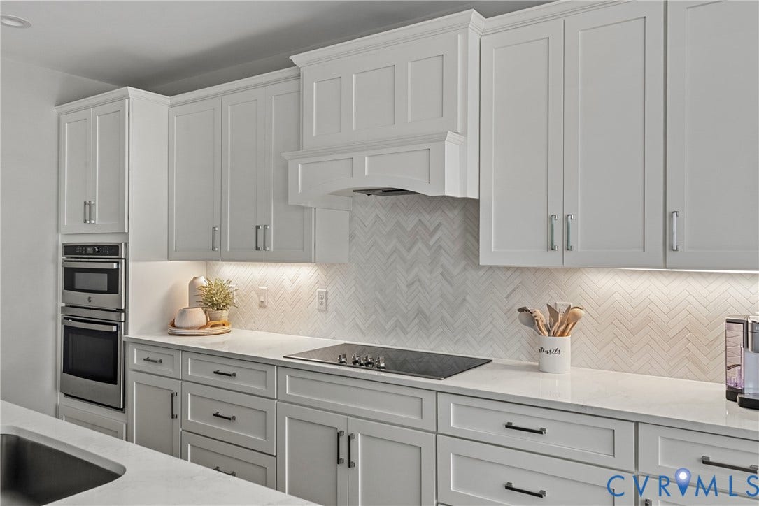 13003 Farrington Place Lane, Farrington Place, Hanover, VA 23059 White shaker cabinetry with crown molding, integrated stainless steel double oven, herringbone tile backsplash, integrated cooktop, and undermount lighting