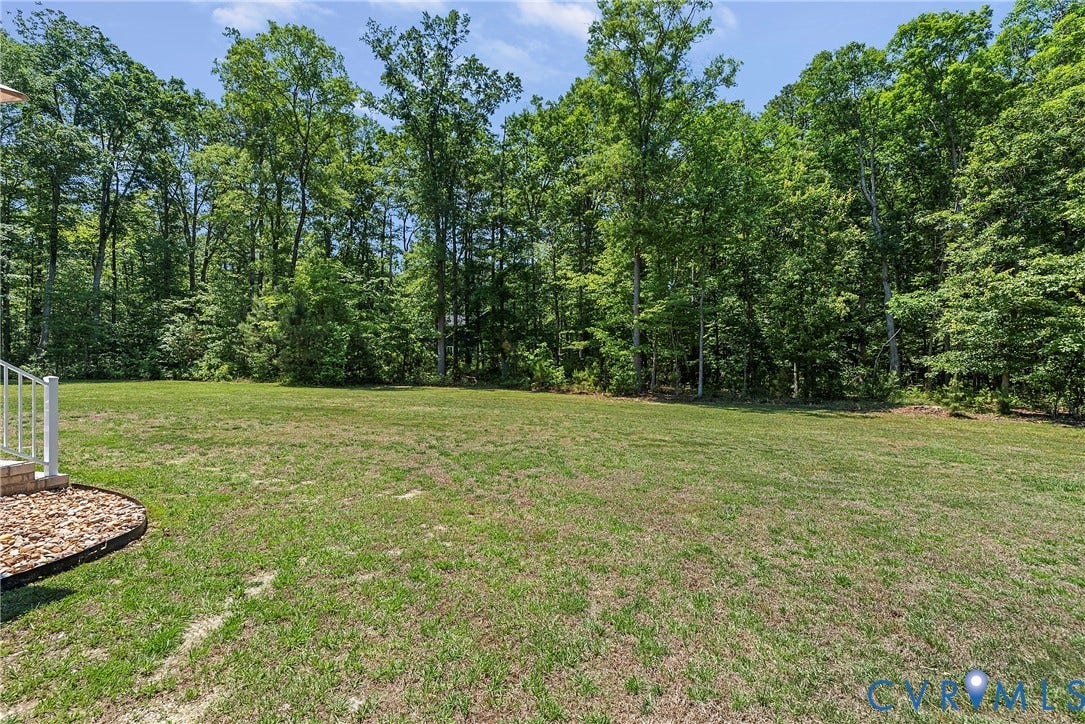 13003 Farrington Place Lane, Farrington Place, Hanover, VA 23059 Expansive green lawn with mature tree backdrop and decorative rock landscaping