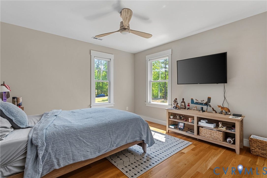 13003 Farrington Place Lane, Farrington Place, Hanover, VA 23059 Hardwood flooring, two windows with white trim, a ceiling fan, and neutral wall paint