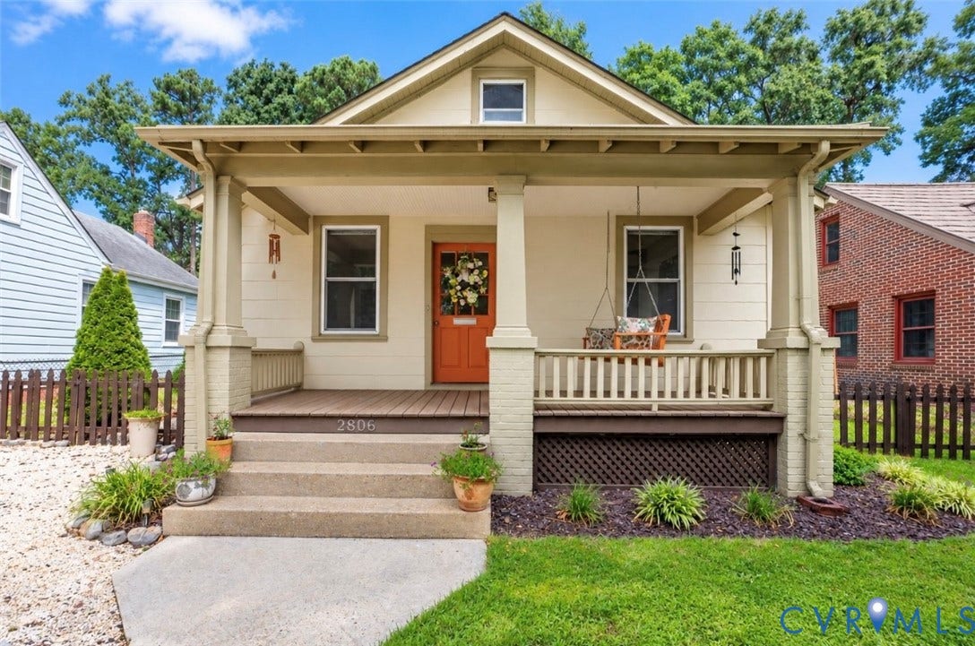 1939 Craftsman-style exterior with a covered front porch, concrete steps, wood-finish decking, and an orange entry door