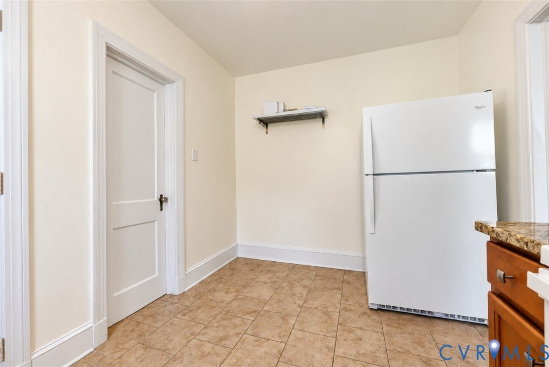 Tile flooring, light-toned walls, white two-panel interior door, baseboard and door trim, built-in shelving