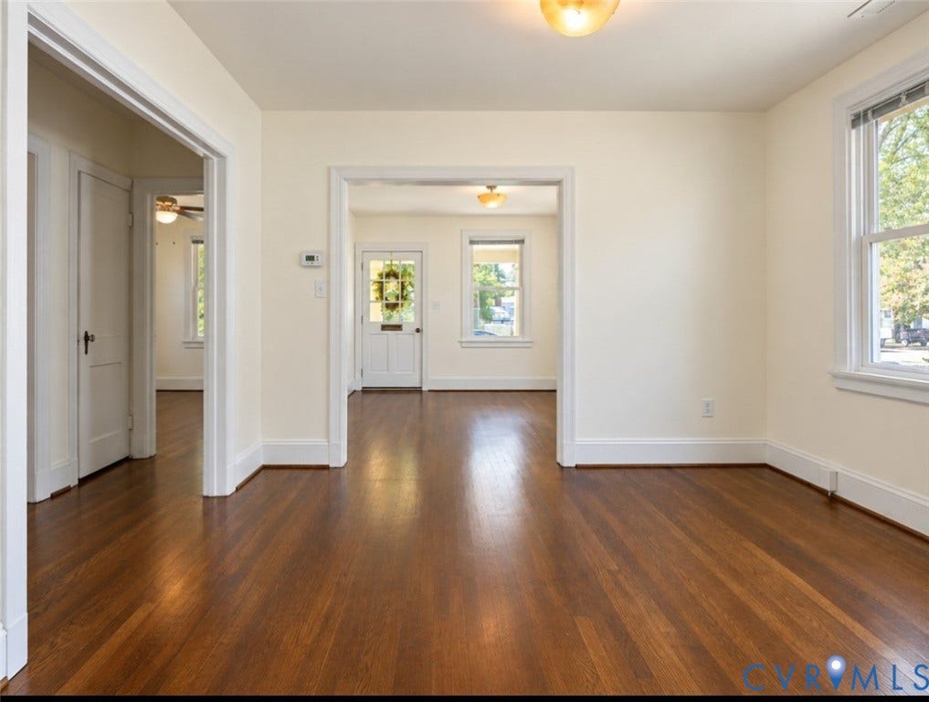 Hardwood flooring throughout, white trim, recessed doorways, and a prominent window