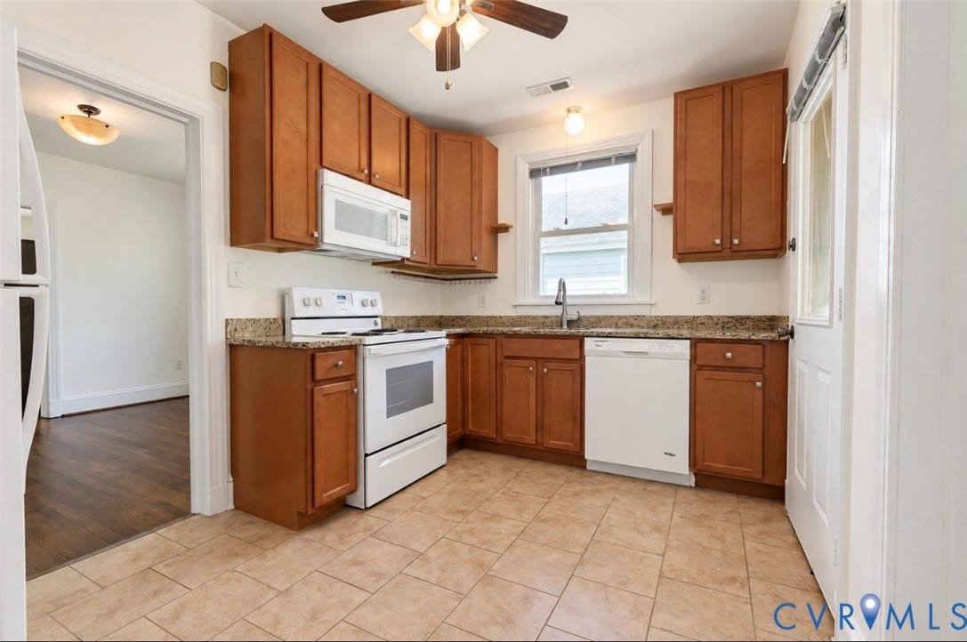 Kitchen featuring tile flooring, wood cabinetry, stone countertops, and white appliances including a refrigerator, range, microwave, and dishwasher