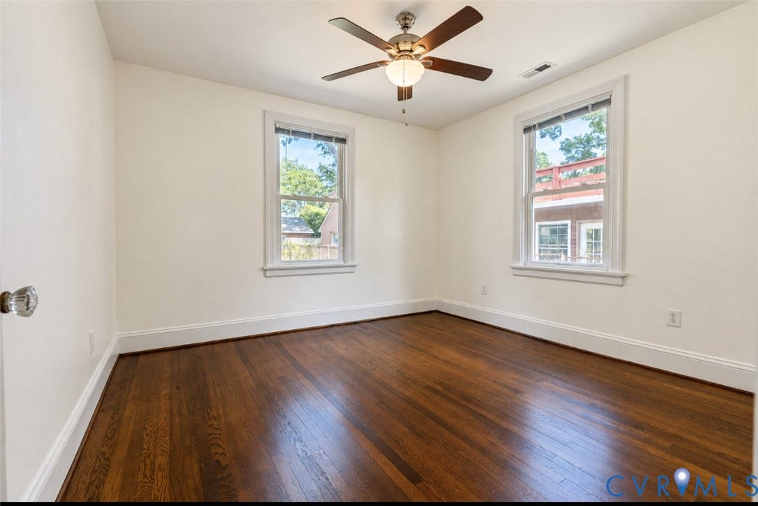 Hardwood flooring, painted walls, ceiling fan with integrated lighting, and two windows with white trim