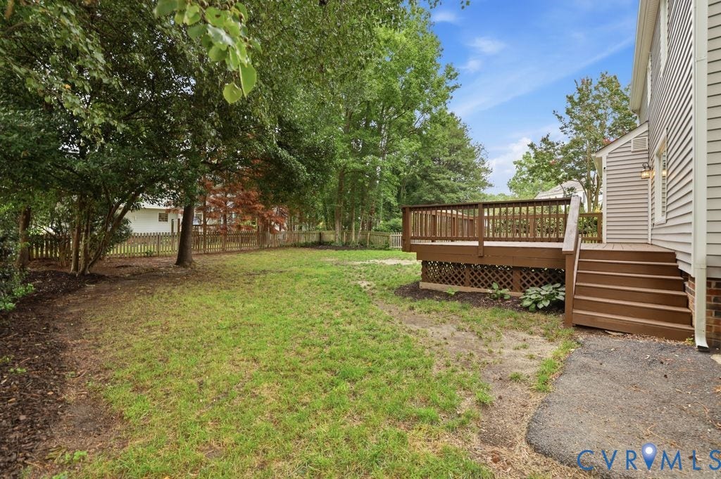 9612 Kingscroft Drive, Glen Allen, VA 23060 Spacious backyard featuring a large elevated wood deck with railing and steps, mature trees, and a partial wood fence