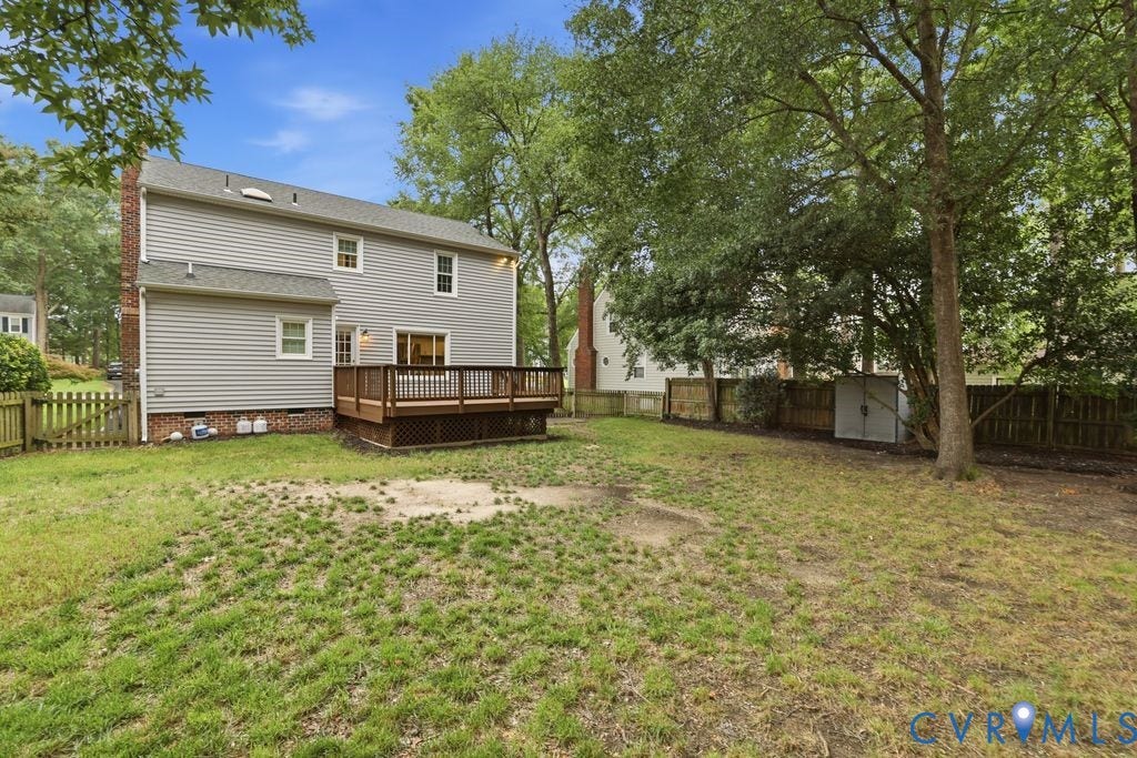 9612 Kingscroft Drive, Glen Allen, VA 23060 Rear exterior featuring a spacious wood deck, gray horizontal siding, a brick chimney, and a fenced backyard with mature trees