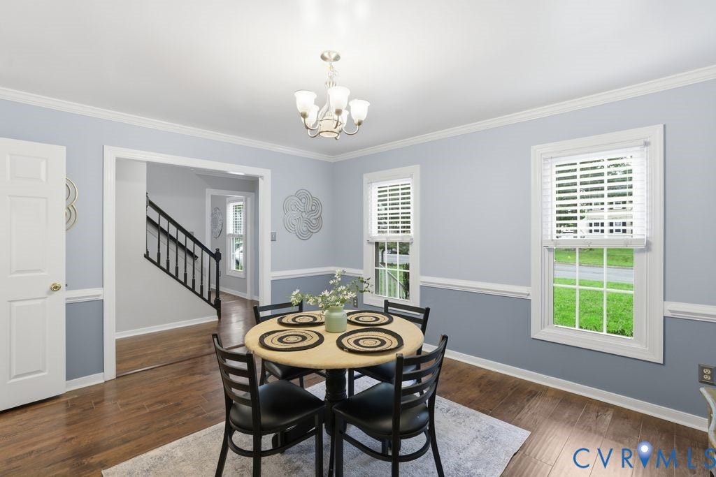 9612 Kingscroft Drive, Glen Allen, VA 23060 Elegant dining room featuring soft blue and gray two-tone wall treatment with chair rail molding, hardwood flooring, and abundant natural light from multi-pane windows and glass doors