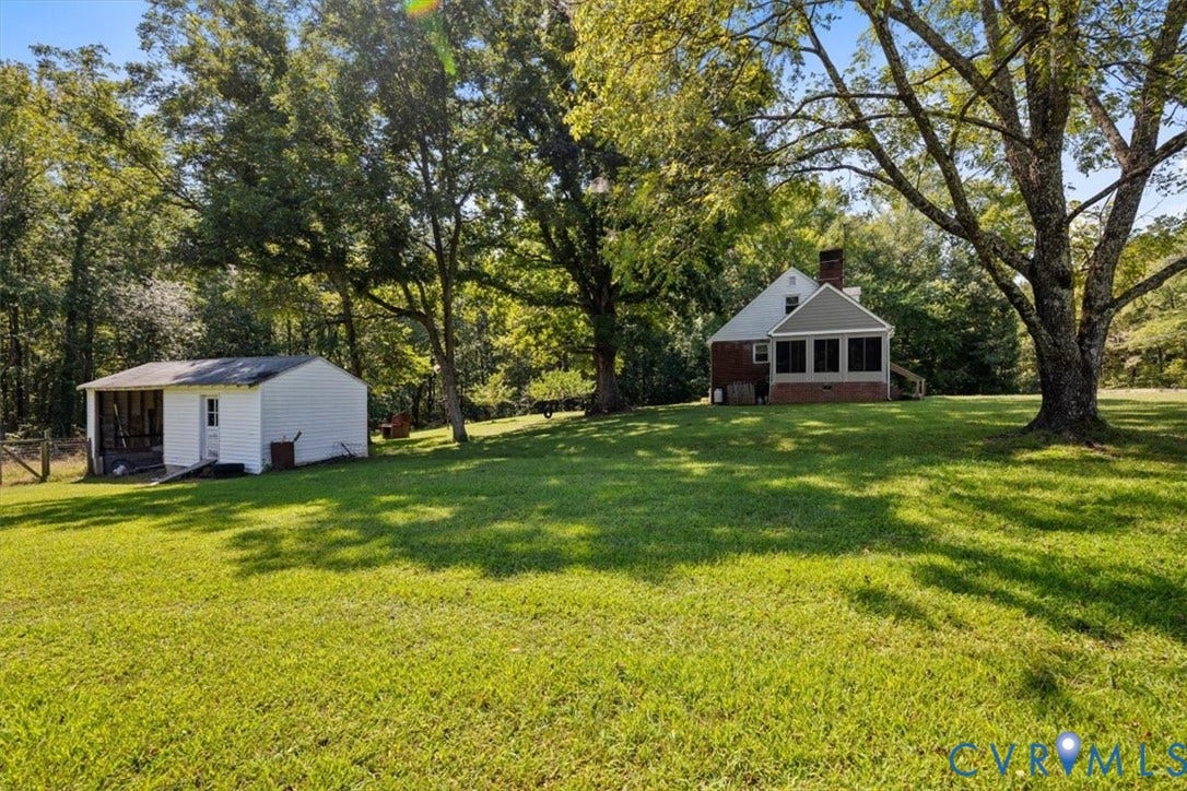 3577 Old Buckingham Road, Powhatan, VA 23139 Expansive green lawn with mature trees, a detached white outbuilding featuring a screened porch, and a brick-sided residence with a screened patio