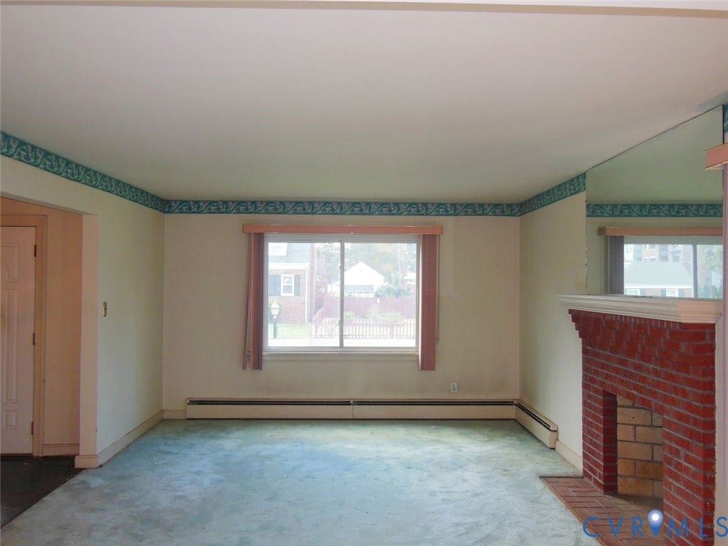 2203 Seminary Avenue, Richmond, VA 23220 Brick fireplace with a white mantel, large window with blinds, and wall-to-wall carpeting