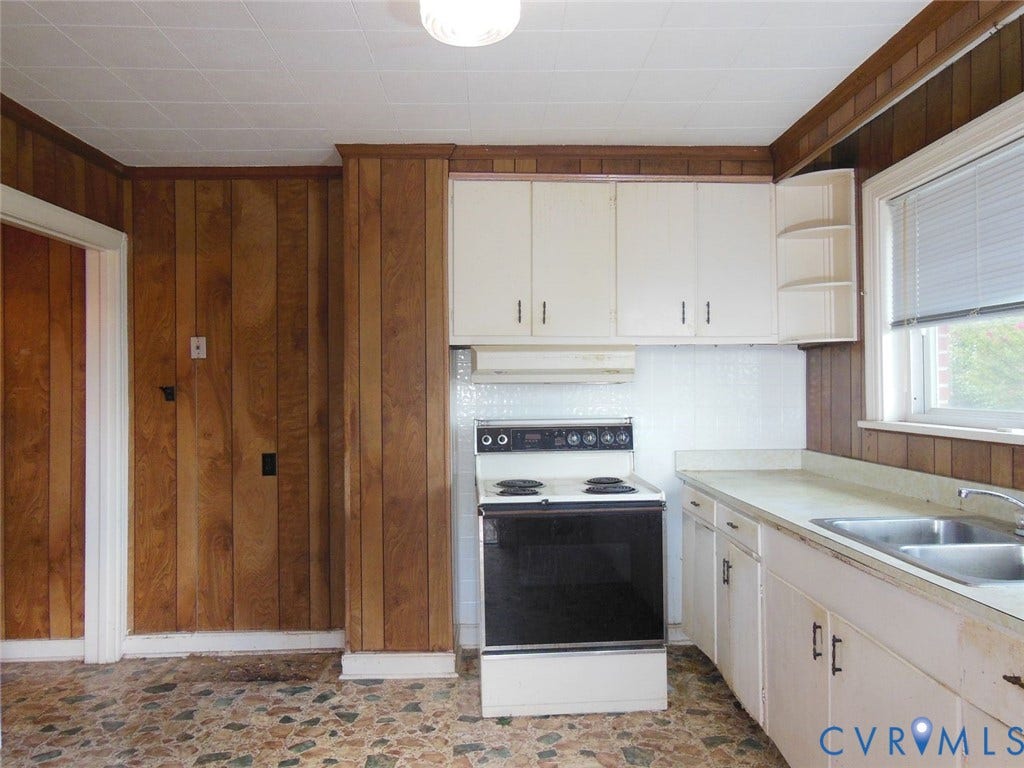 2203 Seminary Avenue, Richmond, VA 23220 Kitchen featuring wood-paneled walls, white upper and lower cabinetry, and a double basin sink
