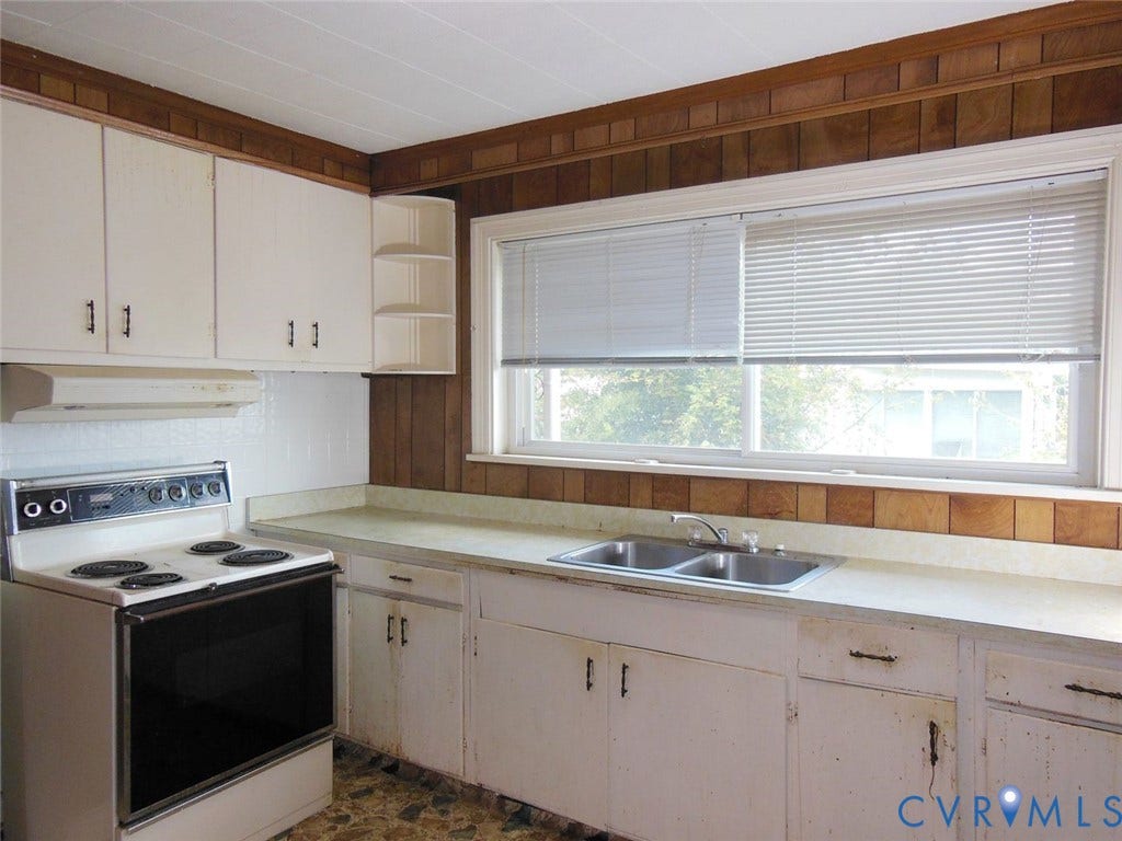 2203 Seminary Avenue, Richmond, VA 23220 White cabinetry with black hardware, double basin stainless steel sink, wood paneling, window with blinds, and built-in shelving