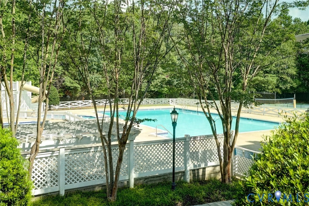 Community pool with waterslide and nearby sand volleyball court
