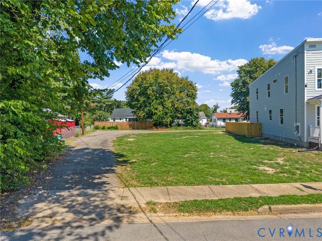 Grass lot with an asphalt driveway and concrete sidewalk
