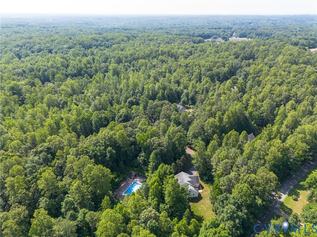 Expansive wooded surroundings with a residential property featuring a pool