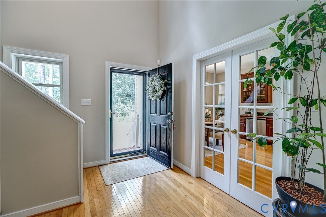 Hardwood flooring throughout the entry, double French doors with transom windows, and a high ceiling