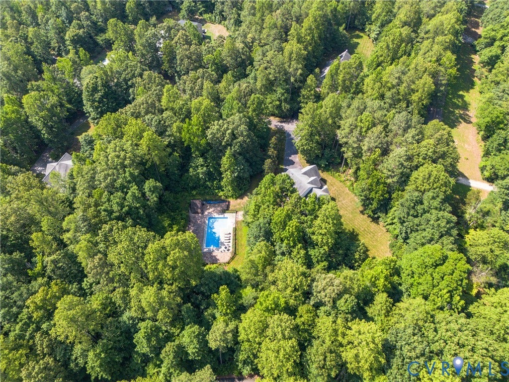 Secluded property featuring a private swimming pool, mature trees, and a gravel driveway