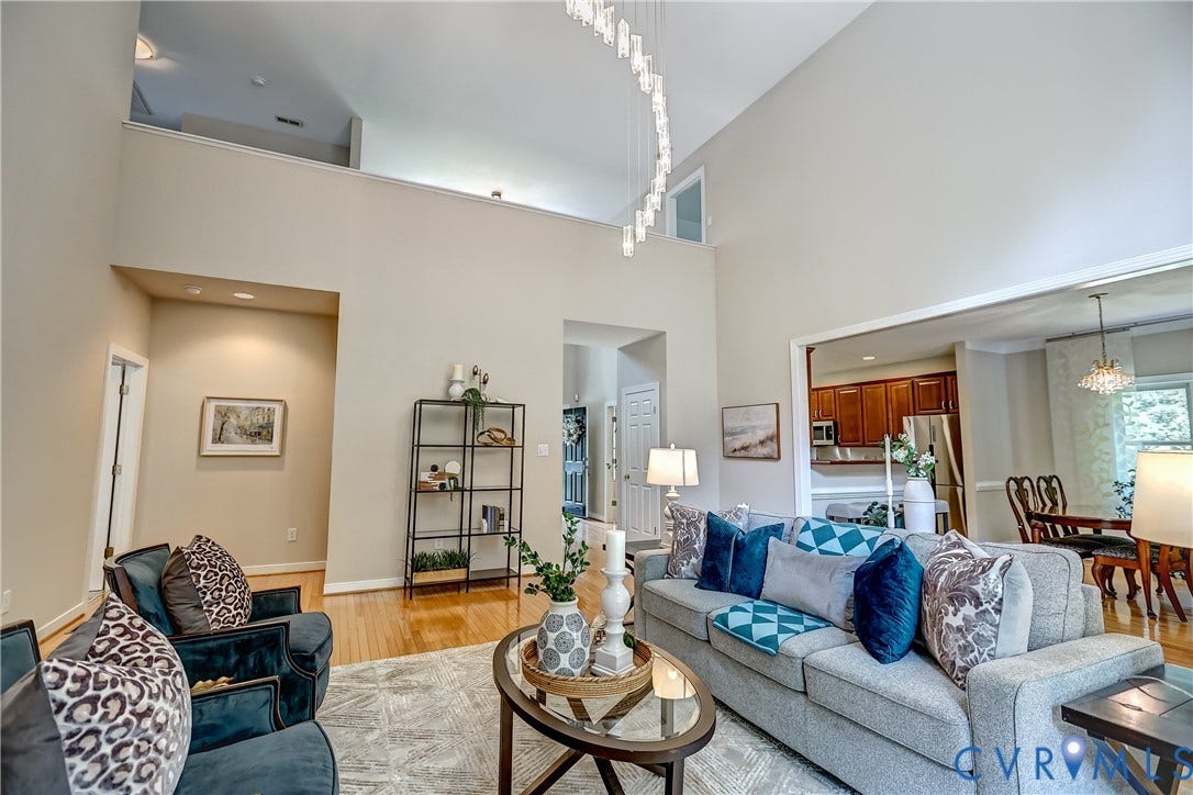 Vaulted ceiling, wood-finish flooring, recessed lighting, and an open doorway leading to a dining area