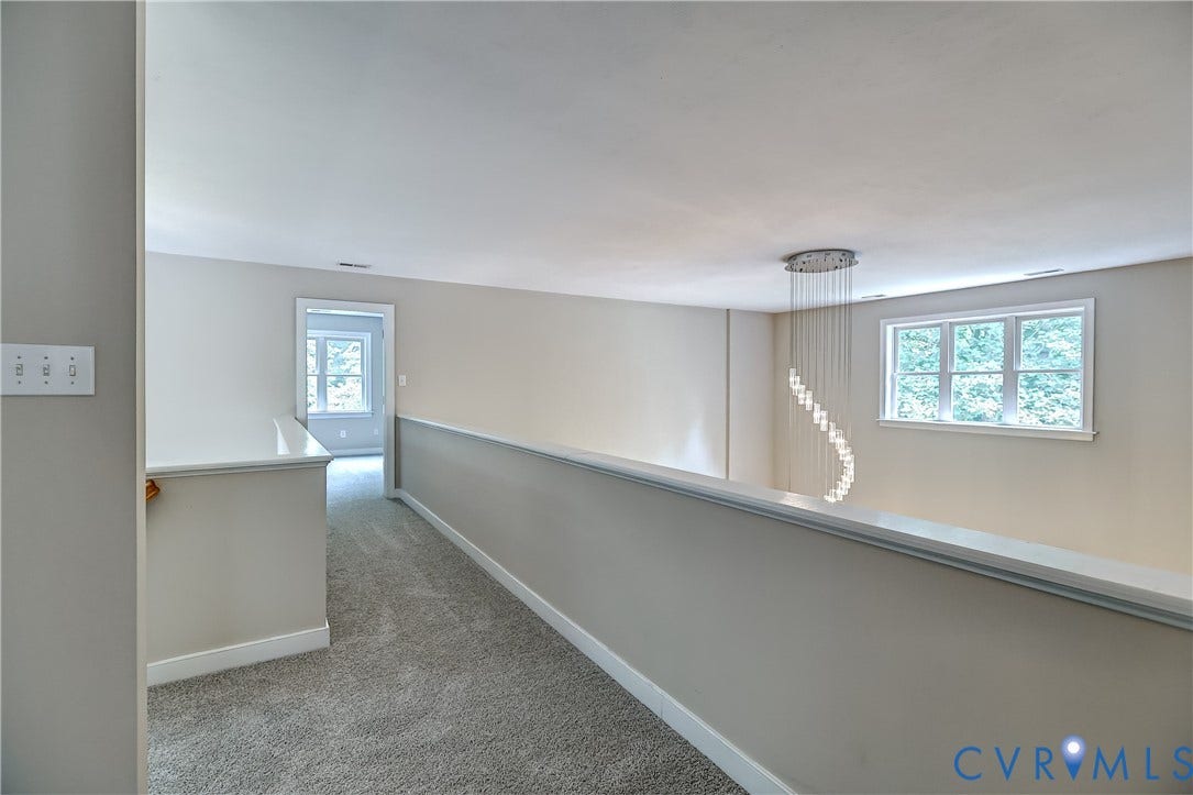 Carpeted open landing featuring a modern chandelier, light neutral paint, and white trim