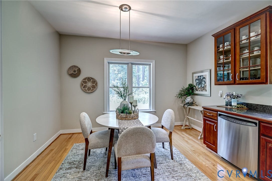 Hardwood-finish flooring, built-in display cabinetry, stainless steel dishwasher, dark countertop, and a window providing natural illumination