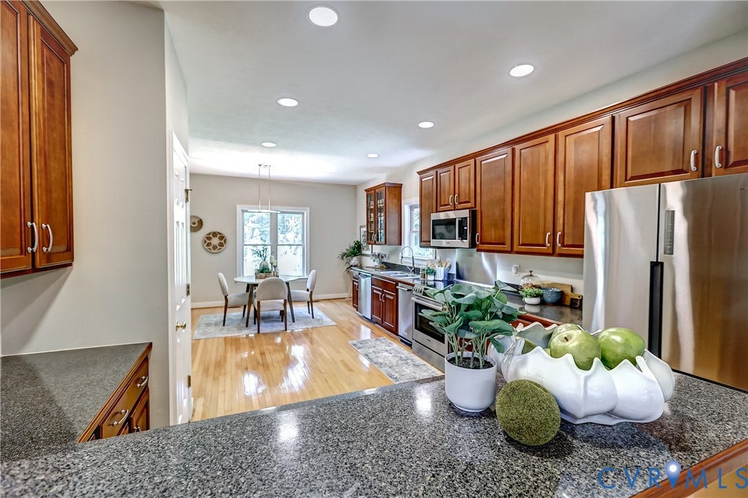 Kitchen with dark stone countertops, wood cabinetry, recessed lighting, and stainless steel appliances