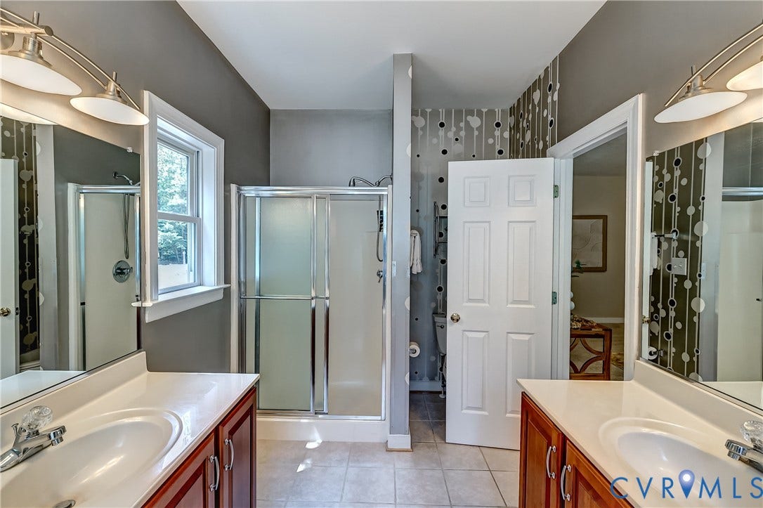 Dual vanity with white countertops, integrated sinks, and wood-finish cabinetry