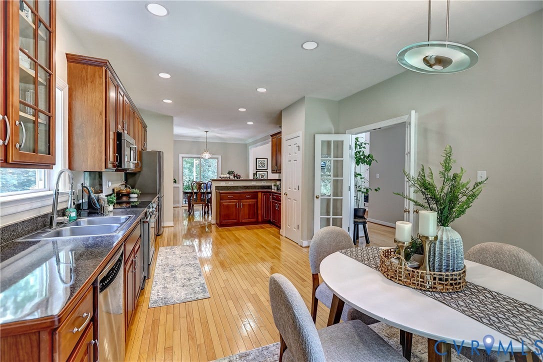 Kitchen with wood-finish cabinetry, stainless steel appliances, dark stone countertops, and hardwood flooring