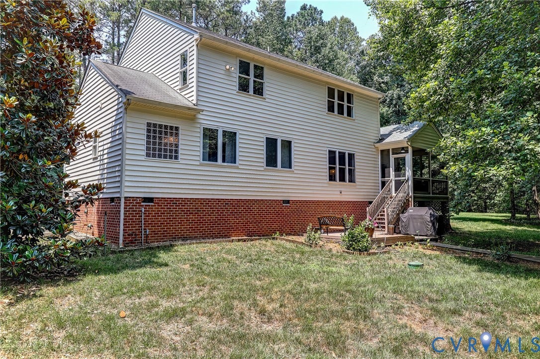 Vinyl siding exterior with a brick foundation, multiple windows, and a screened porch