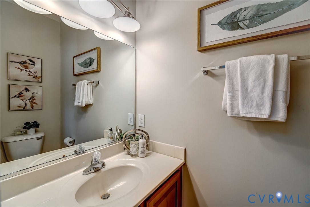 Vanity with an integrated sink, polished chrome faucet, wood-finish cabinetry, and a large wall-mounted mirror