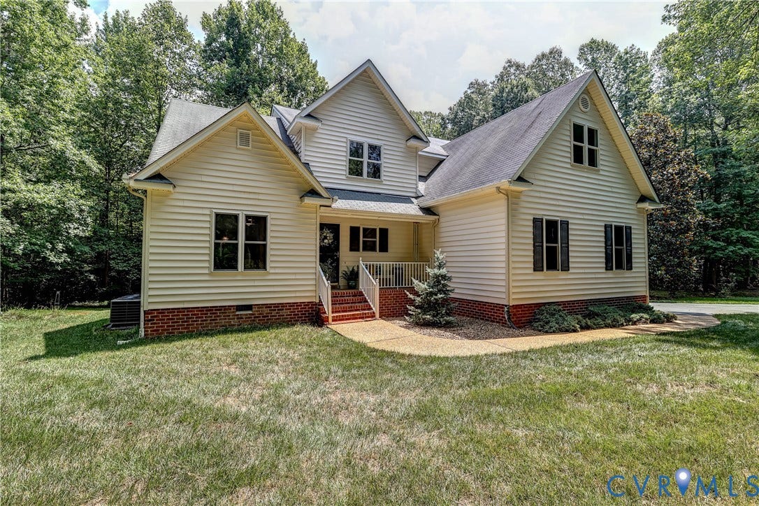 Two-story residence featuring light-toned siding, dark roof shingles, and a brick foundation