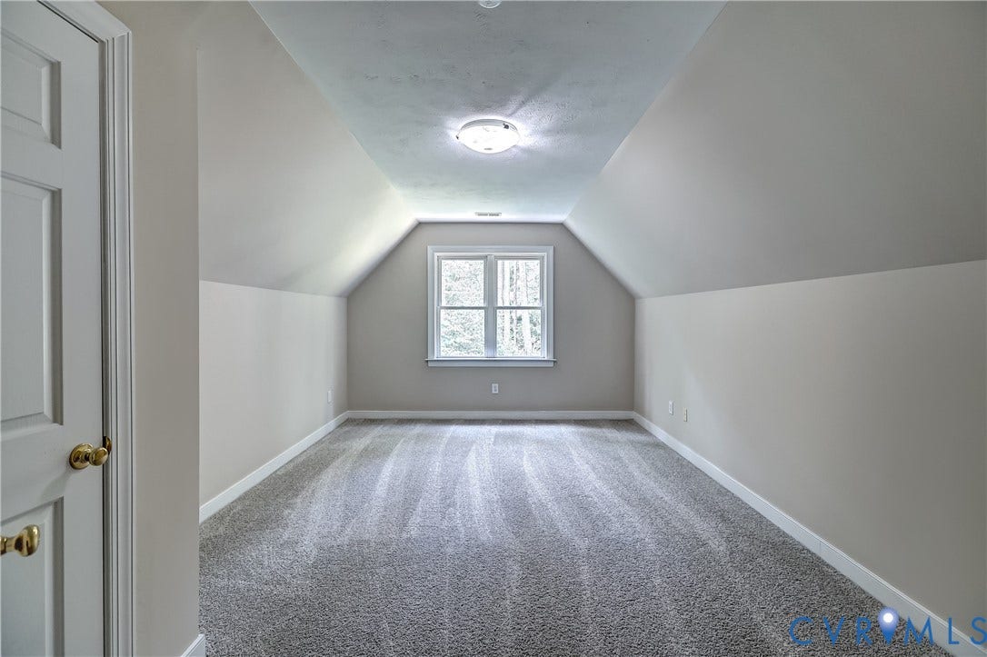 Carpeted room with a vaulted ceiling, a double-hung window, and a flush mount light fixture