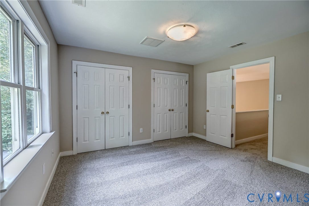 Plush carpeting, two sets of paneled bi-fold closet doors, a single paneled door, and a flush mount ceiling light fixture