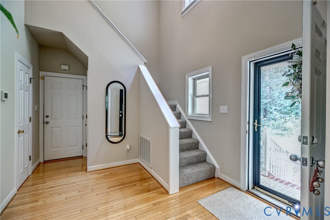 Two-story foyer with high ceilings, wood-finish flooring, and carpeted stairs