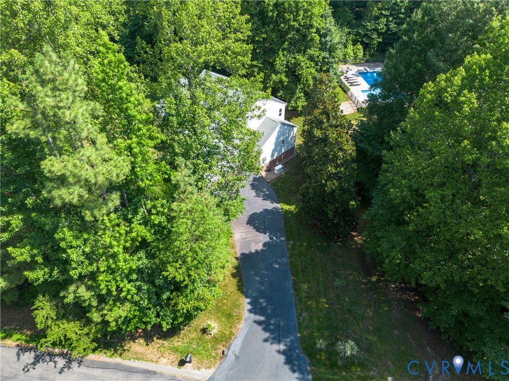 Private driveway leading to a residence with a fenced swimming pool, surrounded by mature trees