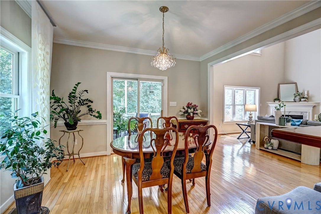Hardwood flooring, crown molding, a crystal chandelier, and a sliding glass door to the exterior