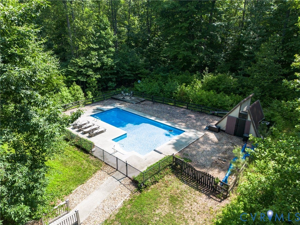 In-ground swimming pool with surrounding concrete decking, secured by perimeter fencing