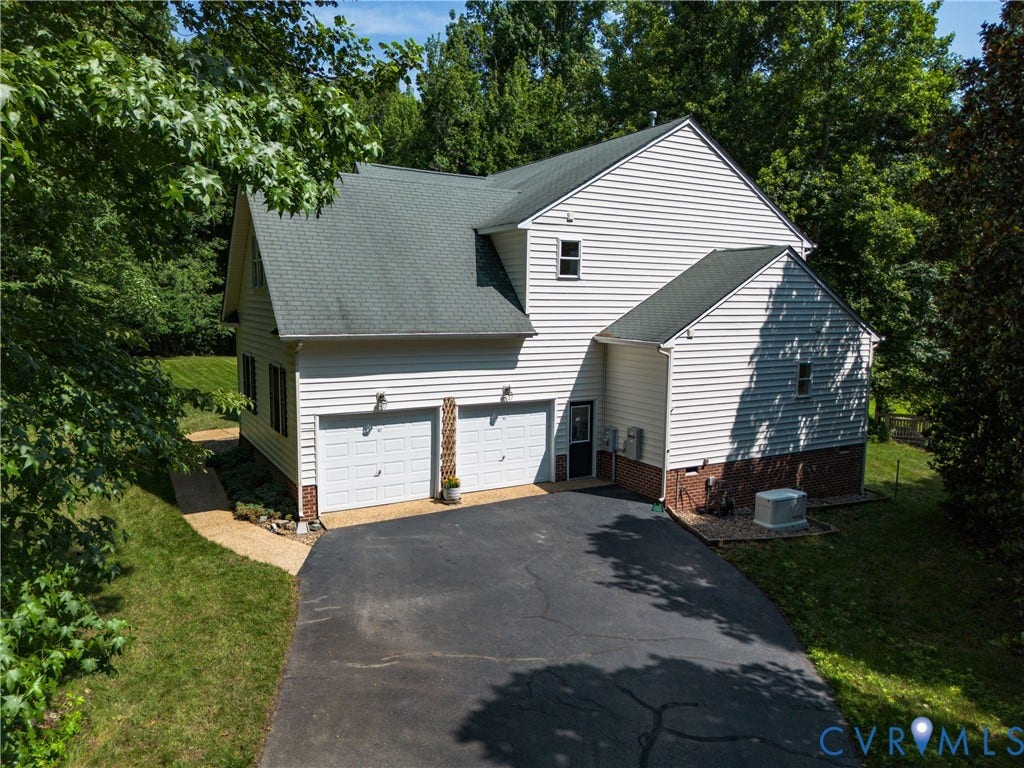 White siding exterior with a dark shingle roof, two-car garage, and a paved driveway